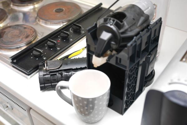 Fixing Your Coffee Machine vs Replacing It A broken coffee machine and a white mug