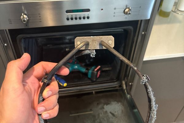 Oven Problems We See in Melbourne Homes A hand holding an oven heating element for replacement