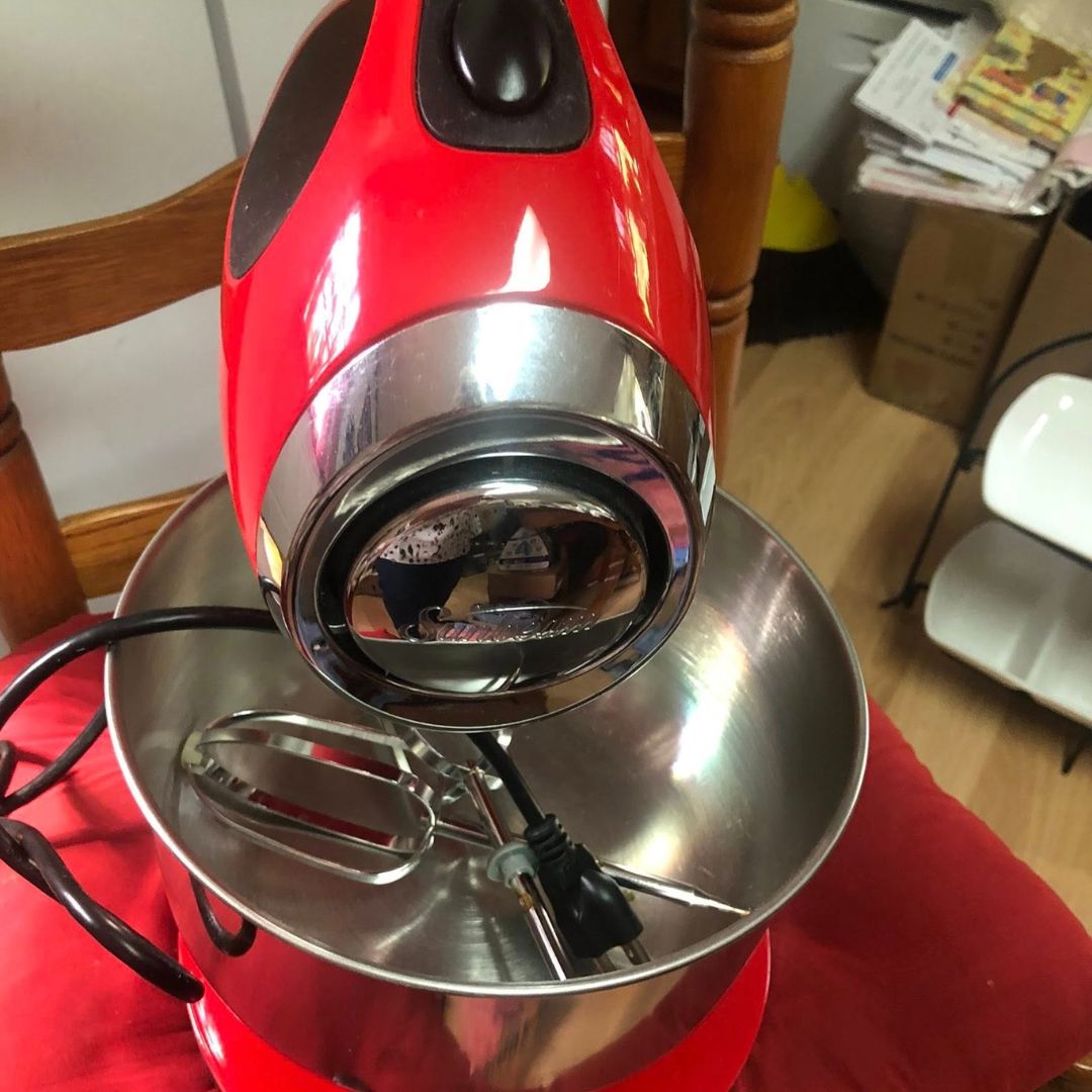 sunbeam-mixer-repair3 The image shows a red hand mixer with a stainless steel bowl. The mixer has a chrome accent around the top and a dark brown/black control button. The beaters are resting inside the bowl.